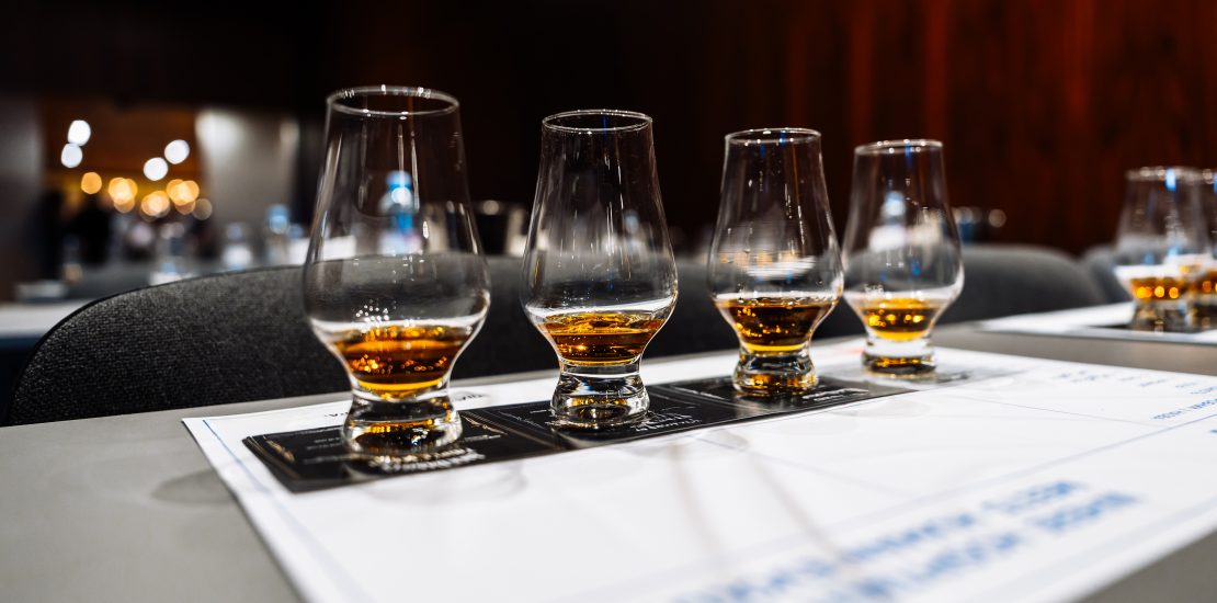 Participants savor various whiskeys at a cocktail preparation event.