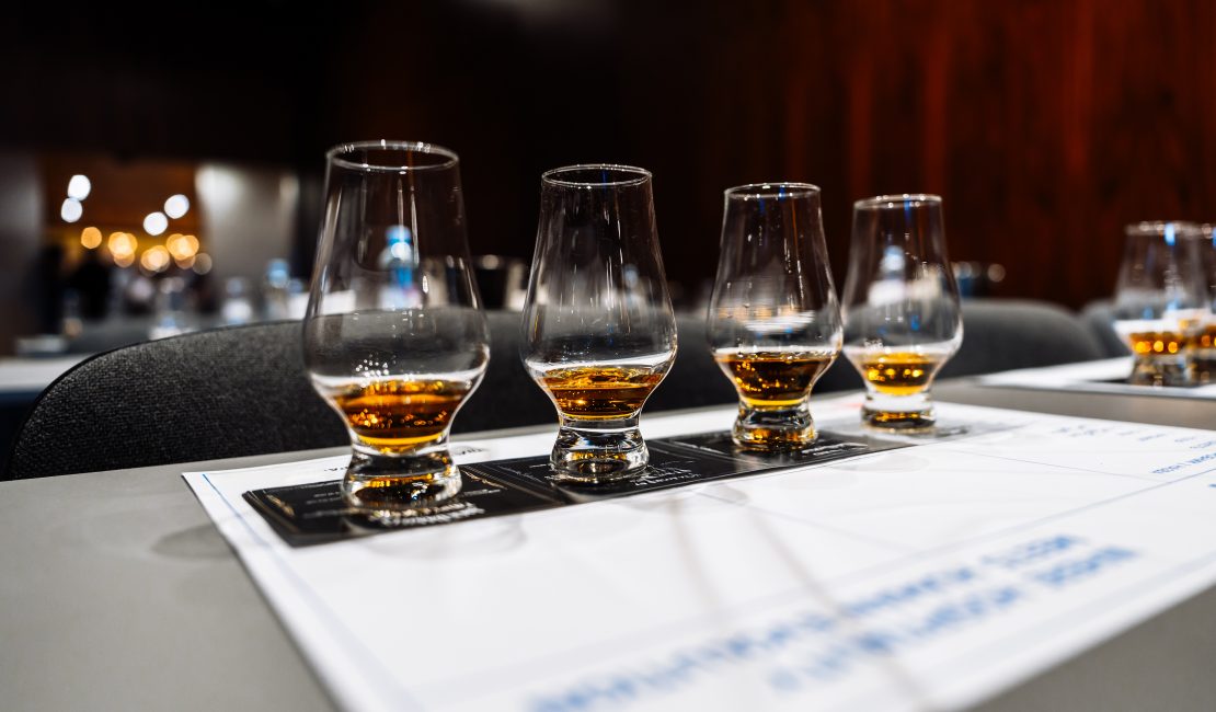 Participants savor various whiskeys at a cocktail preparation event.