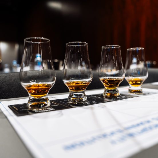 Participants savor various whiskeys at a cocktail preparation event.