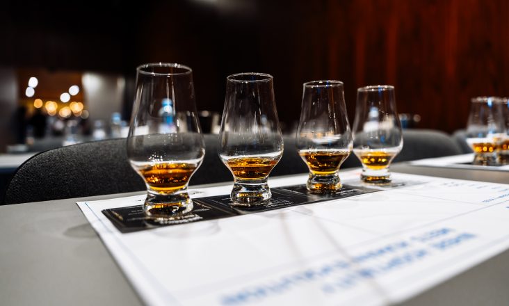 Participants savor various whiskeys at a cocktail preparation event.