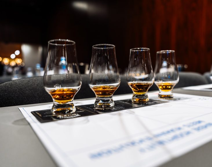 Participants savor various whiskeys at a cocktail preparation event.