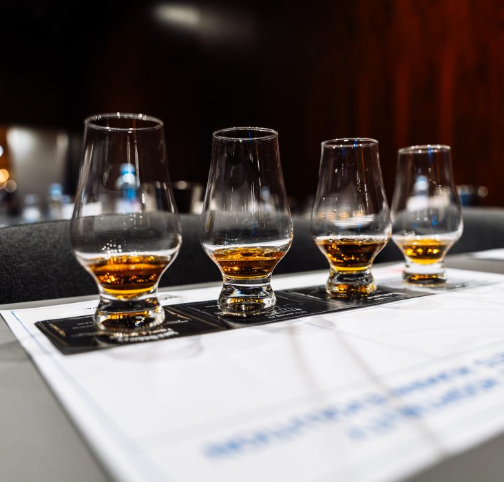 Participants savor various whiskeys at a cocktail preparation event.