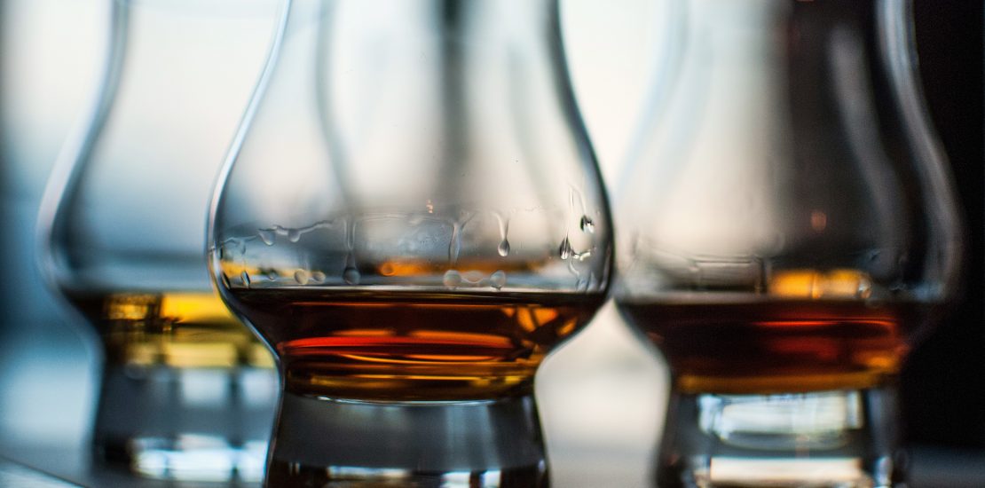 A closeup shot of three glasses of whiskey on blurred background