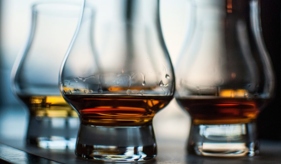 A closeup shot of three glasses of whiskey on blurred background