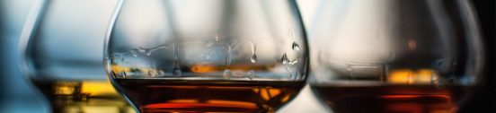 A closeup shot of three glasses of whiskey on blurred background