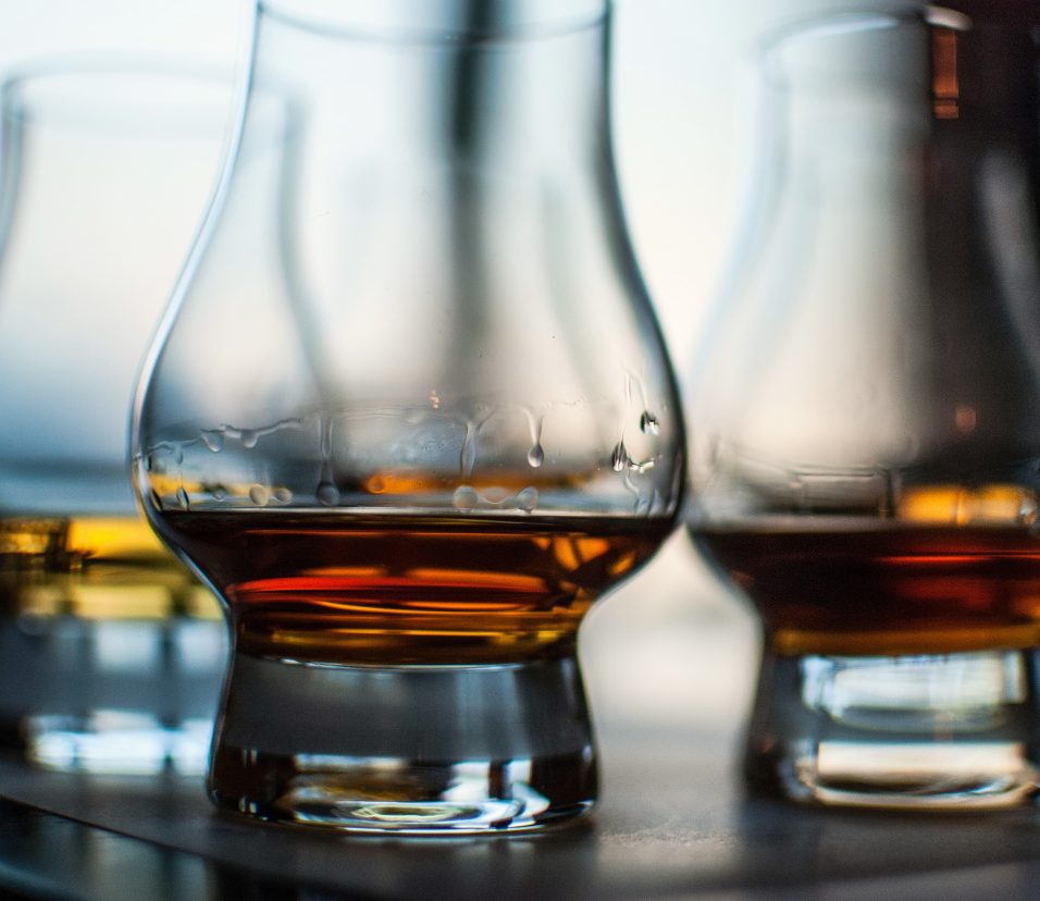 A closeup shot of three glasses of whiskey on blurred background